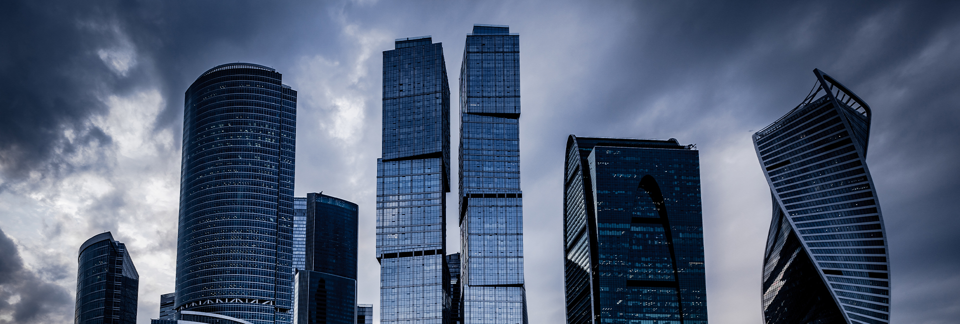 A group of tall buildings with a cloudy sky in the background.