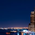 A city skyline at night with lights reflecting off the water.