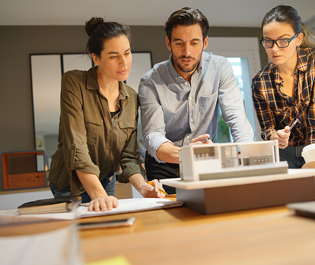 Three people looking at a model of a house.