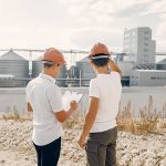 Two men in hard hats looking at a map.