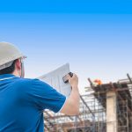 A man holding papers and wearing hard hat.