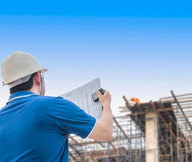 A man holding papers and wearing hard hat.