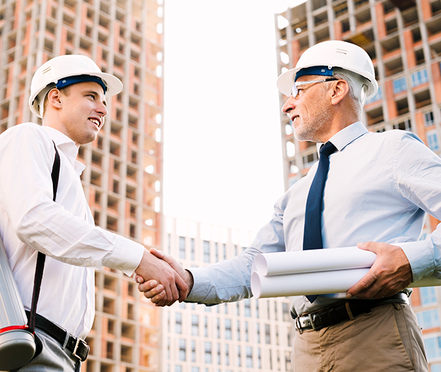 Two men shaking hands in front of a building.