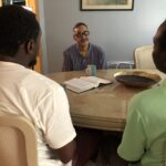 Three men engaged in conversation at a table.