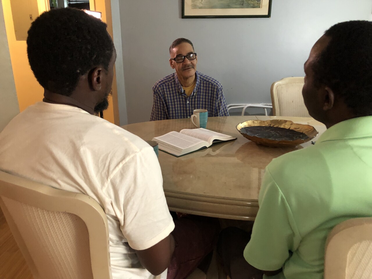 Three men engaged in conversation at a table.